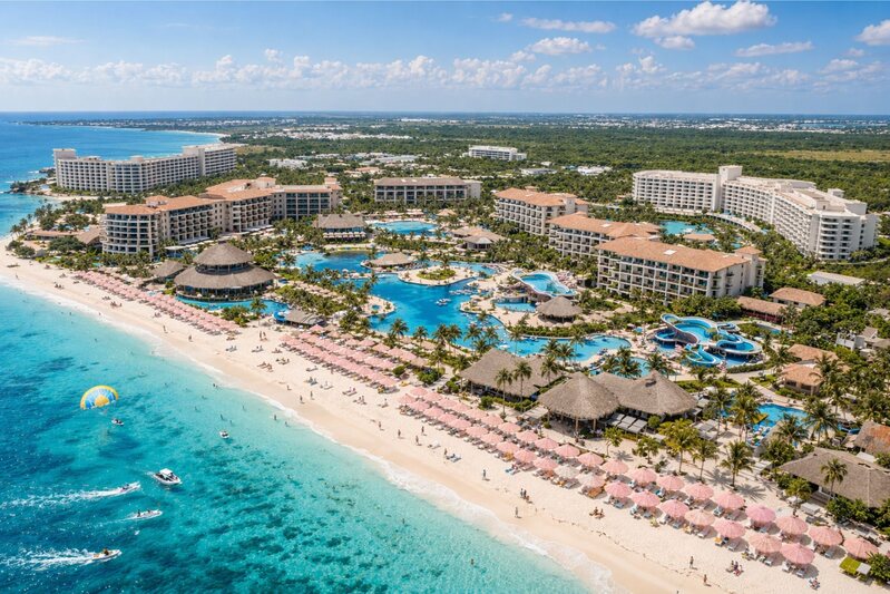 Aerial view of beachfront multi-building resort with pools and turquoise water